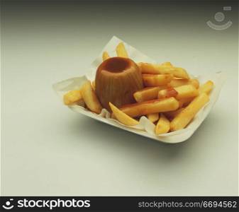 a pie/pudding with fries/chips and gravy in a takeaway tray