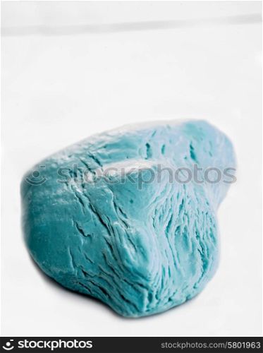 A piece of blue soap, all but used up, lies on a white background, revealing a unique shape with lines, cracks, and textures.