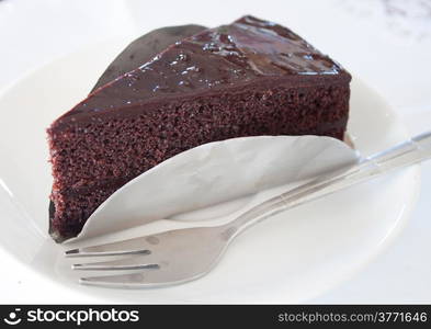 A piece of dark chocolate cake on white isolated background