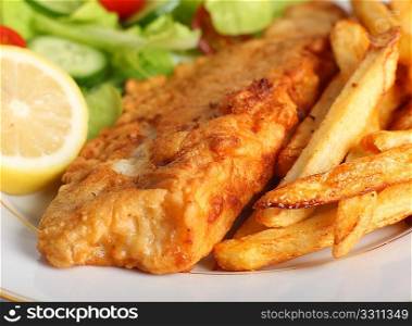 A piece of fish in batter served with french fried potato chips, lemon and a lettuce, rocket, cucumber and tomato salad.