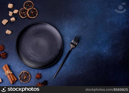 A piece of fresh delicious cake with nuts and chocolate on a black plate against a dark blue background. Desserts and sweets to the dinner table. A piece of fresh delicious cake with nuts and chocolate on a black plate against a dark blue background