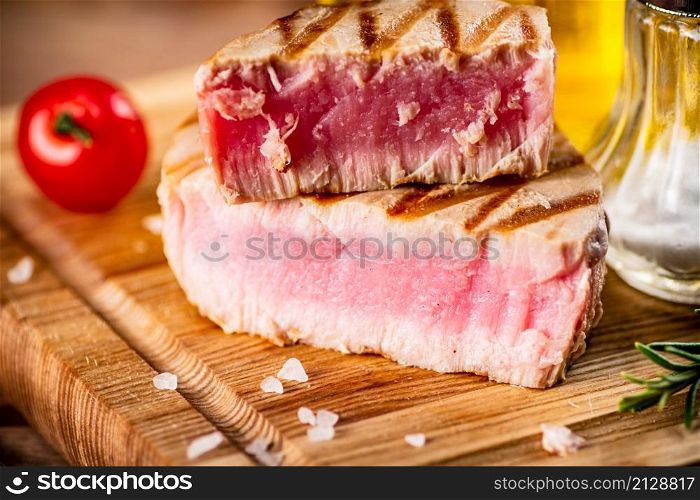 A piece of grilled tuna on a cutting board. On a wooden background. High quality photo. A piece of grilled tuna on a cutting board.