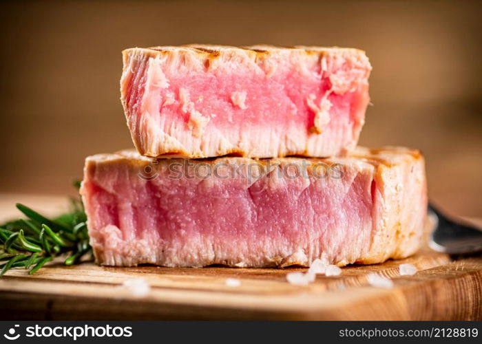 A piece of grilled tuna on a cutting board. On a wooden background. High quality photo. A piece of grilled tuna on a cutting board.