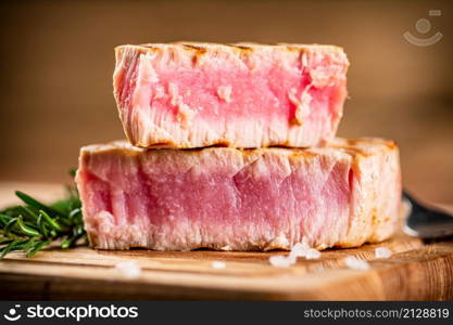 A piece of grilled tuna on a cutting board. On a wooden background. High quality photo. A piece of grilled tuna on a cutting board.