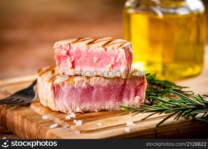 A piece of grilled tuna on a cutting board. On a wooden background. High quality photo. A piece of grilled tuna on a cutting board.