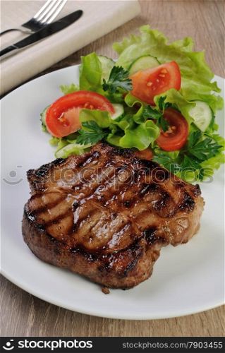 A piece of juicy pork steak grilled with a salad