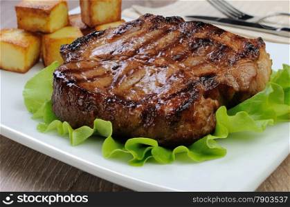 A piece of juicy pork steak grilled with roasted potatoes