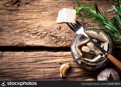 A piece of salted herring on a fork. On a wooden background. High quality photo. A piece of salted herring on a fork.