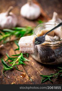A piece of salted herring on a fork. On a wooden background. High quality photo. A piece of salted herring on a fork.