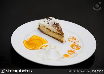 a piece of sponge cake with white and dark chocolate, served with orange slices and syrup