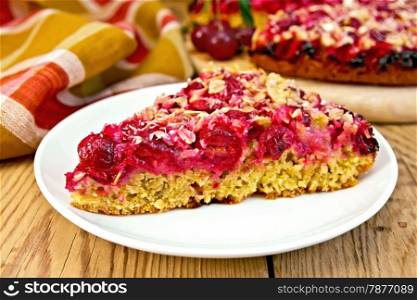 A piece of sweet cake with cherries on a plate, napkin on a wooden boards background