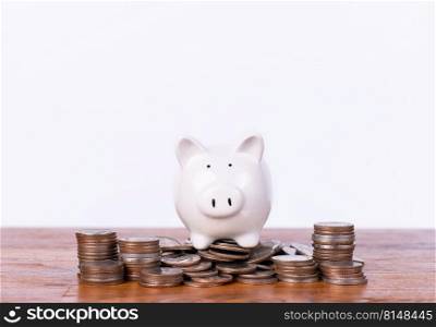A piggy bank is placed on a pile of coins, Saving money for the happiness of life and goals in life. Money coins stack for growing growth with piggy bank, Saving investment with target.