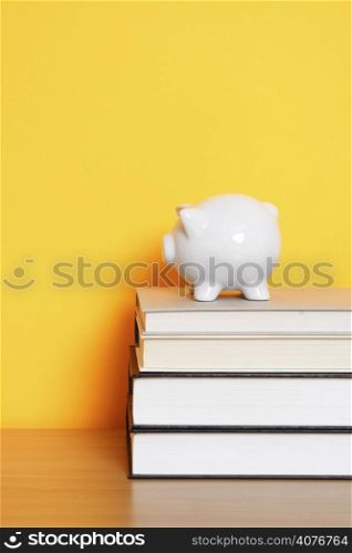A piggy bank on top of a stack of books, can be used for saving for college design