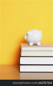 A piggy bank on top of a stack of books, can be used for saving for college design