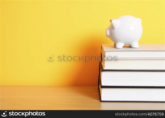 A piggy bank on top of a stack of books, good for saving for college theme