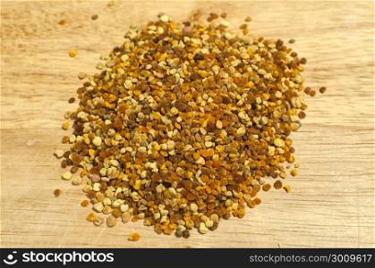 A pile of bee pollen grains closeup on wooden board background