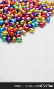 A pile of colored easter chocolate eggs with copy space