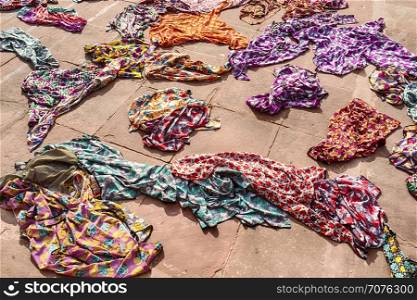 A pile of colorful hijabs, or head coverings, for use by tourists are scattered on the ground by the entrance of the Jama Masjid mosque in Delhi, India.