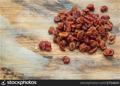 a pile of dried cranberries on a grunge painted wood background