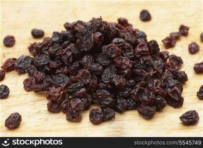 A pile of dried currants on a wooden chopping board