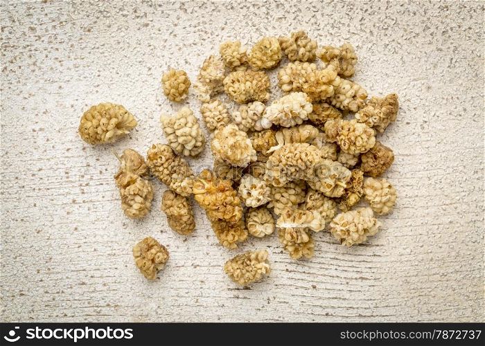 a pile of dried white mulberry fruit against rustic barn wood
