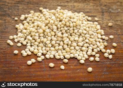 a pile of gluten free white sorghum grain on a grunge wood