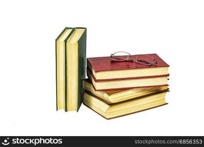 A pile of hard-bound books and reading glasses lie on a light background