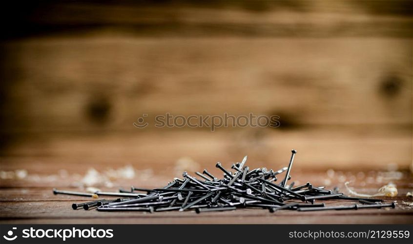 A pile of nails on the table. On a wooden background. High quality photo. A pile of nails on the table.