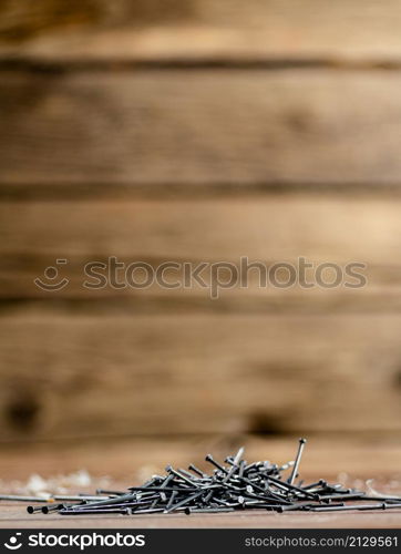 A pile of nails on the table. On a wooden background. High quality photo. A pile of nails on the table.