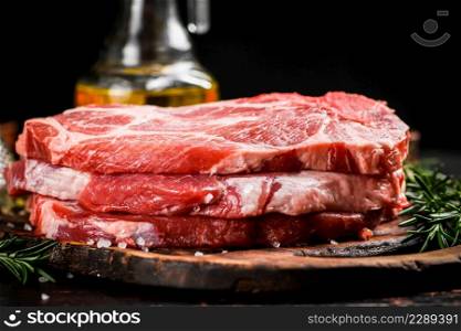 A pile of raw pork steak on a cutting board. On a black background. High quality photo. A pile of raw pork steak on a cutting board.