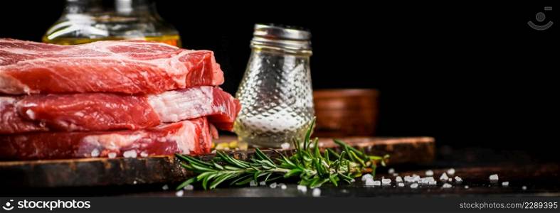 A pile of raw pork steak on a cutting board. On a black background. High quality photo. A pile of raw pork steak on a cutting board.
