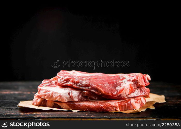 A pile of raw pork steak on the table. On a black background. High quality photo. A pile of raw pork steak on the table.