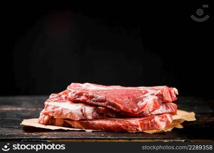 A pile of raw pork steak on the table. On a black background. High quality photo. A pile of raw pork steak on the table.