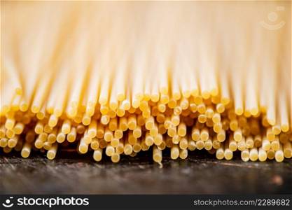 A pile of spaghetti dry on the table. Against a dark background. High quality photo. A pile of spaghetti dry on the table.
