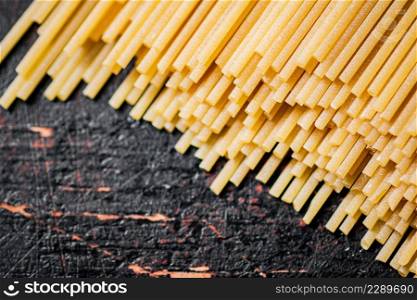 A pile of spaghetti dry on the table. Against a dark background. High quality photo. A pile of spaghetti dry on the table.