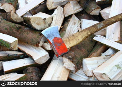 A pile of split firewood logs with an ax