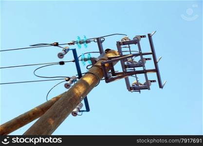 A pillar of power line with a line isolator against the sky
