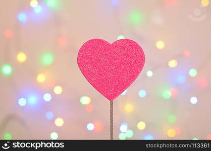 A pink glitter heart isolated against an out of focus light background