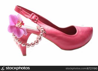 A pink high heel ladies shoe, a pearl necklace and an orchid