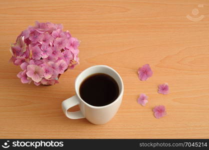 A pink Hydrangea with a white mug