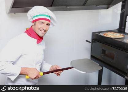 a pizza cook in front of an oven