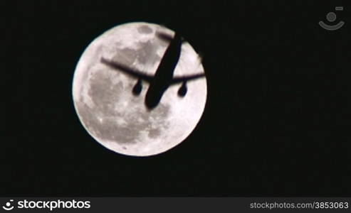A plane crossing the face of the moon.An airplane is silhouetted against a full moon in the sky.Fly me to the moon.No effects, just live action.