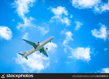 A plane flying in the blue sky with white clouds