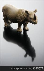 A plastic figurine of a rhinoceros and its reflection on a black background