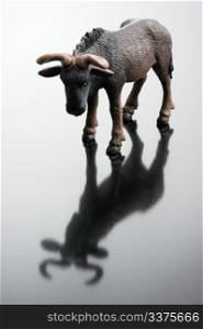 A plastic figurine of antelope and its reflection on a black background