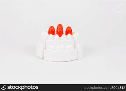 a plastic toy children&rsquo;s cake with white cream on a white background. plastic toy children&rsquo;s cake with white cream on a white background