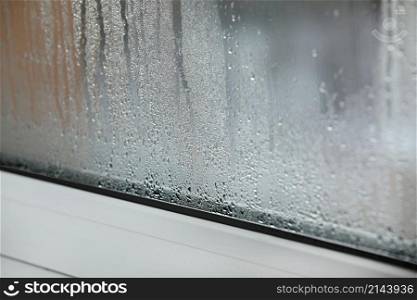 a plastic window with condensation of water on the glass. Double glazed PVC window. Concept: defective plastic window with condensation, temperature difference, cooling, humidity in the room. a plastic window with condensation of water on the glass. Double glazed PVC window. Concept: defective plastic window with condensation, temperature difference, cooling, humidity in the room.