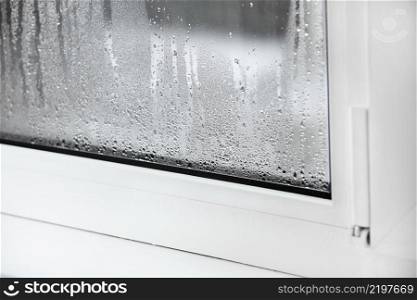 a plastic window with condensation of water on the glass. Double glazed PVC window. Concept  defective plastic window with condensation, temperature difference, cooling, humidity in the room. a plastic window with condensation of water on the glass. Double glazed PVC window. Concept  defective plastic window with condensation, temperature difference, cooling, humidity in the room.