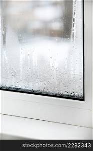 a plastic window with condensation of water on the glass. Double glazed PVC window. Concept: defective plastic window with condensation, temperature difference, cooling, humidity in the room. a plastic window with condensation of water on the glass. Double glazed PVC window. Concept: defective plastic window with condensation, temperature difference, cooling, humidity in the room.