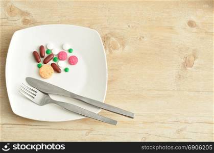 A plate filled with pills displayed with a fork and knife